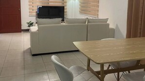 Un salon moderne avec un canapé, un téléviseur et une table à manger avec des chaises.