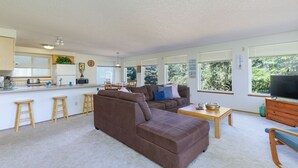 A modern living room with a brown sectional sofa, a wooden coffee table, and a television. - Pacific Drift at Proposal Rock w/Beach Access (Neskowin)