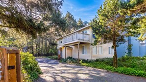 A two-story building with a balcony, surrounded by trees and a gravel driveway. - Pacific Drift at Proposal Rock w/Beach Access (Neskowin)