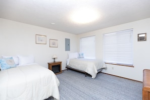 A bedroom with two beds, a nightstand, a lamp, and framed pictures on the wall. - Pacific Drift at Proposal Rock w/Beach Access (Neskowin)