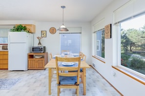 A kitchen with a dining table, chairs, a microwave, and a refrigerator. - Pacific Drift at Proposal Rock w/Beach Access (Neskowin)