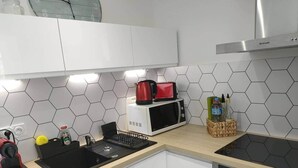 Moderni keittiö, jossa on valkoiset kaapit, mikroaaltouuni, liesi ja pesuallas.