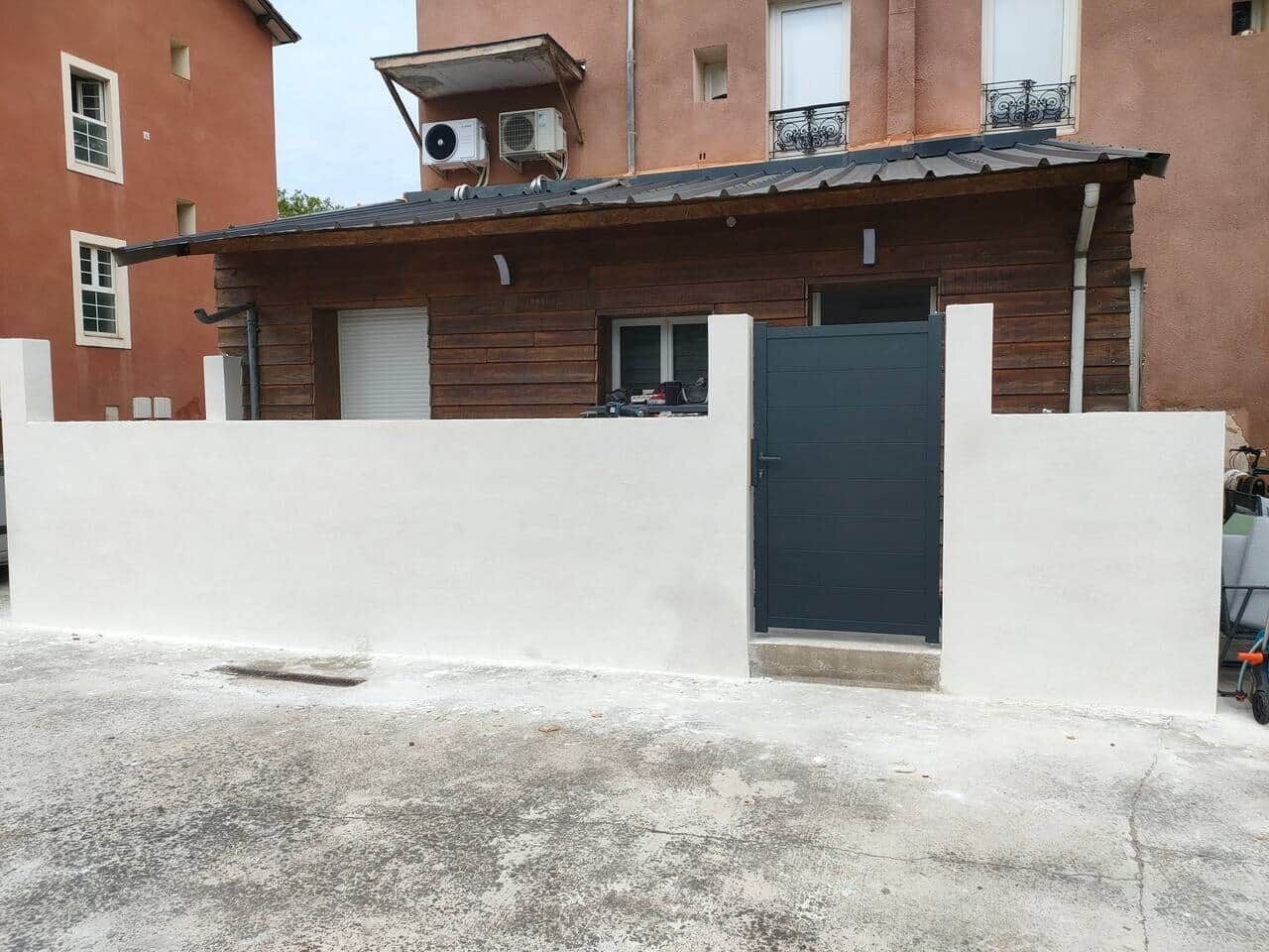 Un edificio con fachada de madera, puerta oscura y pared blanca al frente.