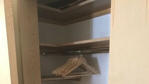 Un placard en bois avec trois étagères et une tringle pour suspendre les vêtements.