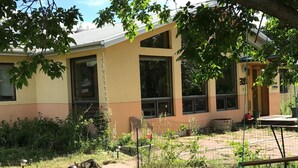 Un bâtiment doté de grandes fenêtres, un espace jardin agrémenté d’un sentier, et un espace extérieur clôturé.