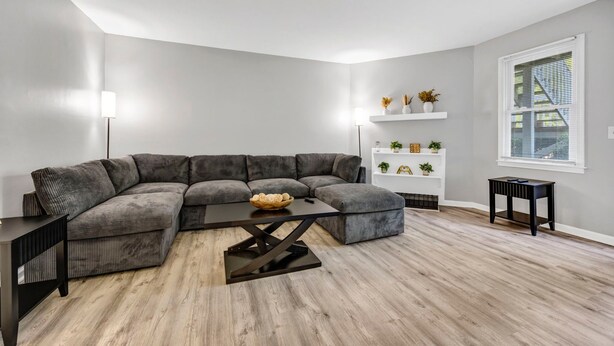 Un salon moderne avec un canapé d’angle, une table basse et une petite table d’appoint.