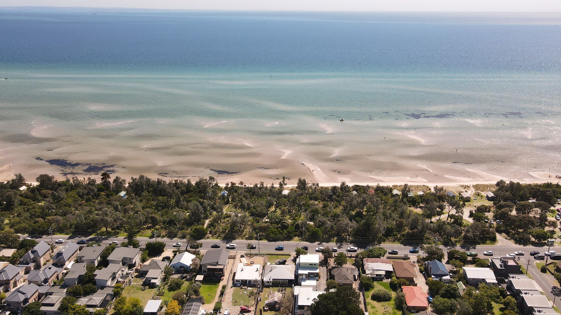 Luftaufnahme einer Küstenwohngegend mit Häusern, einem Strand und freiem Blick auf den Ozean.