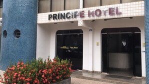 Entrada d'un hotel amb façana enrajolada, un rètol que diu "PRINCIPE HOTEL" i un banc de flors a la façana.
