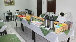 Un aparador tipus bufet amb diferents aliments i begudes sobre una taula, envoltat de cadires.