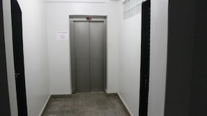 Un passadís estret amb una porta d'ascensor tancada i un senyal que indica que l'ascensor no funciona.