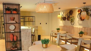 A modern dining area with round tables, white chairs, and a central light fixture. - Get Sense Beira Mar (Joao Pessoa)