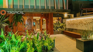 A hotel entrance with a tropical theme, including a sign with the word 'TROPICAL' and a reception desk. - Get Sense Beira Mar (Joao Pessoa)