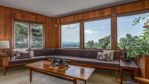 A living room with a large window, a sofa, a coffee table, and a view of the outdoors. - Secluded Mid-Century Retreat w/ mtn views, near WLU, VMI (Rockbridge County)