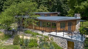 A modern wooden cabin with a stone foundation, large windows, and a patio area. - Secluded Mid-Century Retreat w/ mtn views, near WLU, VMI (Rockbridge County)