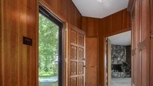 A hallway with wooden paneling, a carpeted floor, and a view of a stone wall and greenery outside. - Secluded Mid-Century Retreat w/ mtn views, near WLU, VMI (Rockbridge County)
