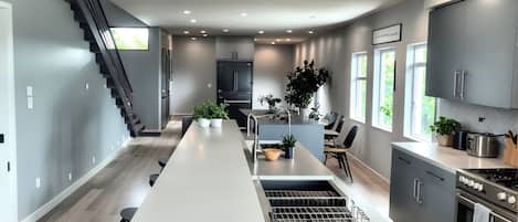 A modern kitchen with a central island, stainless steel appliances, and a staircase leading to another level.