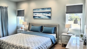 A modern bedroom with a bed, bedside tables, a nightstand, a lamp, a painting of the ocean, and a window with a view. - 𝐵𝑒𝒶𝓊𝓉𝒾𝒻𝓊𝓁 Townhouse Haven from Hollywood—with PRIVATE BALCONY VIEW (Los Angeles)