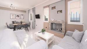 Ett modernt vardagsrum med en öppen spis, en matplats och en soffa.