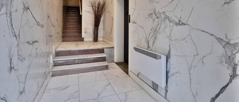 A marble-floored hallway with a staircase leading to another room.