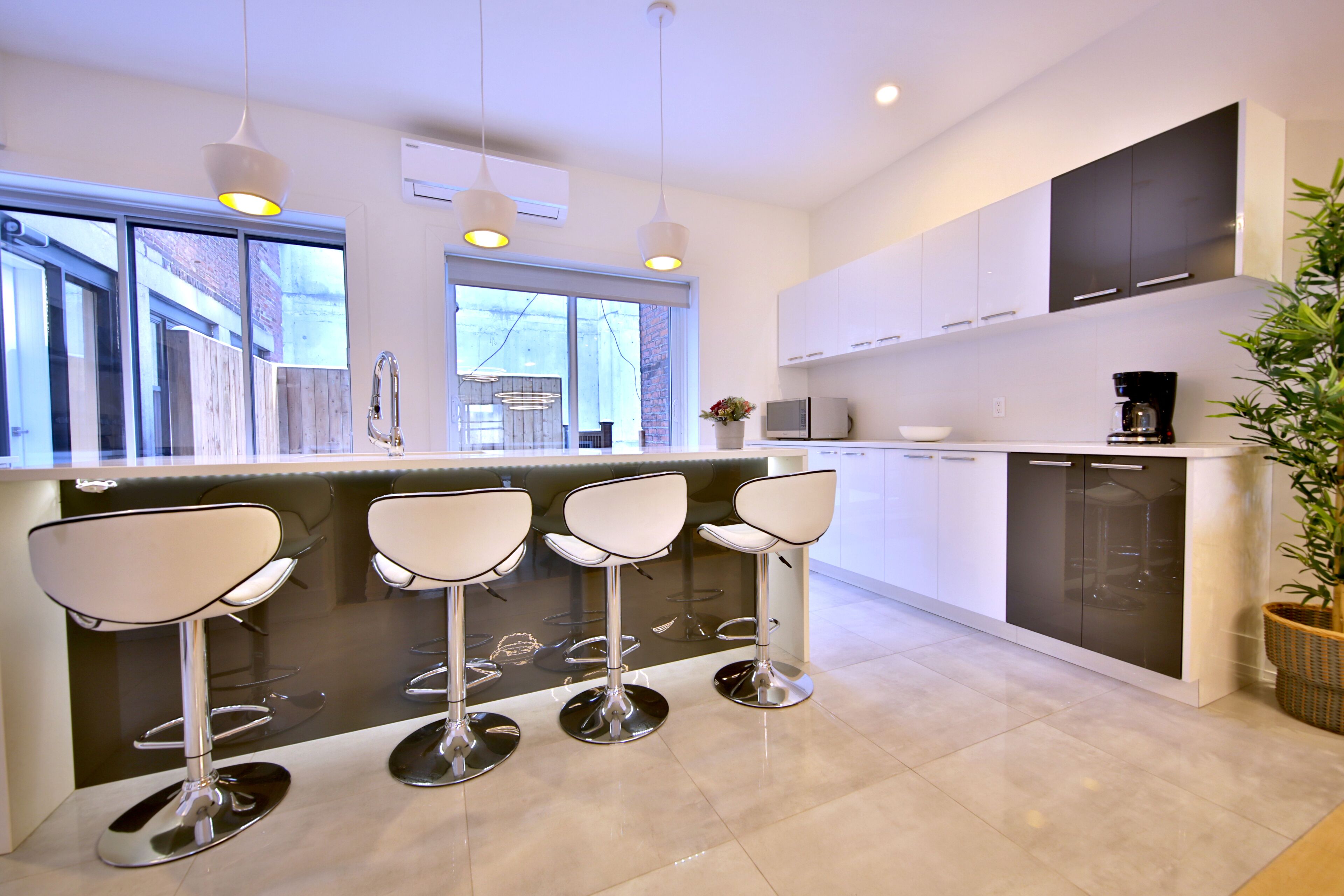 A modern kitchen with a bar area, stainless steel appliances, and a large window.