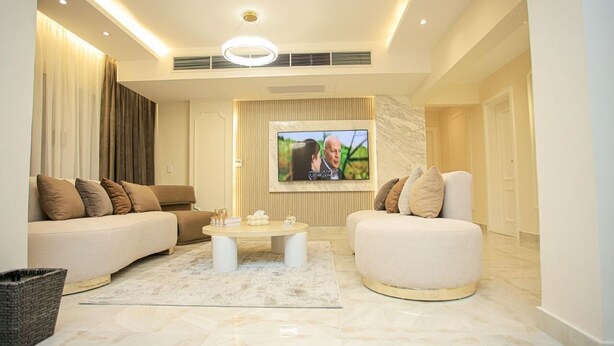 A modern living room with a sofa, armchair, coffee table, and TV.