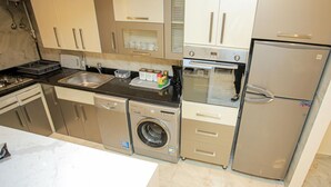 A compact kitchen with a dishwasher, washing machine, oven, and refrigerator.