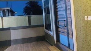 A room with a wooden floor, a sliding glass door, and a view of palm trees outside. - Salma's Place (Kumasi)