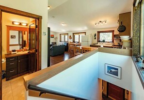 A spacious kitchen with wooden cabinets, a dining area with a table and chairs, and a large window providing natural light. - The Barn: Private Deck & Mountain Panoramas (Fernie)