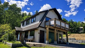 A two-story house with a balcony, a garage, and a well-maintained garden. - The Barn: Private Deck & Mountain Panoramas (Fernie)