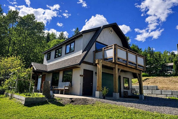 A two-story house with a balcony, a garage, and a well-maintained garden. - The Barn: Private Deck & Mountain Panoramas (Fernie)