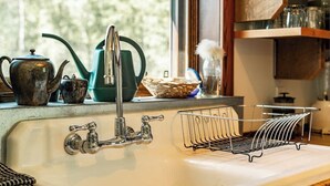A kitchen sink with a vintage faucet, a tea kettle, and a dish rack. - The Barn: Private Deck & Mountain Panoramas (Fernie)