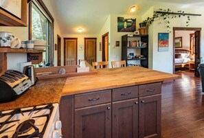 A kitchen with a central island, wooden cabinets, and a gas stove. - The Barn: Private Deck & Mountain Panoramas (Fernie)