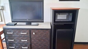 Ein Flachbildfernseher auf einem Schrank mit einer Mikrowelle und einem kleinen Kühlschrank.