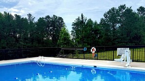 Ein Schwimmbecken mit Rettungsschwimmerstuhl und Hinweisschild für die Poolregeln.