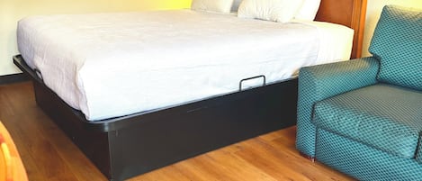 Une chambre d’hôtel avec un grand lit, une tête de lit en bois, un canapé de couleur turquoise et un tableau encadré au mur.