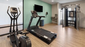 A gym with cardio equipment, a TV, and a window.