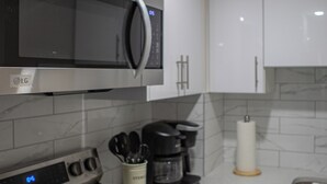 A modern kitchen with stainless steel appliances, white cabinets, and a marble backsplash. - Cozy 2BR/2BA Suite | 10 Mins to Airport | Private Entry & Kitchen (Calgary)