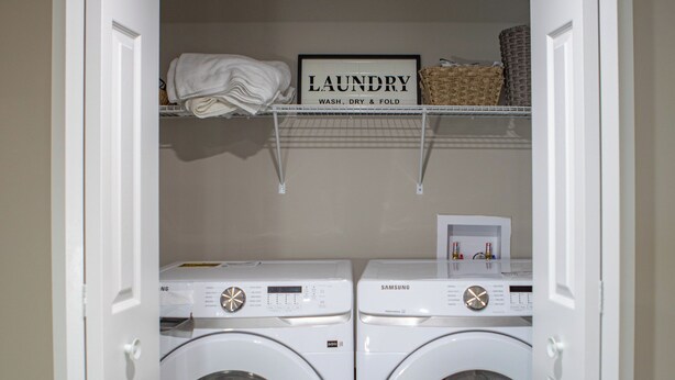 A laundry room with two white front-loading washing machines, a shelf with folded towels, and a sign that reads "LAUNDRY WASH. DRY & FOLD." - Cozy 2BR/2BA Suite | 10 Mins to Airport | Private Entry & Kitchen (Calgary)
