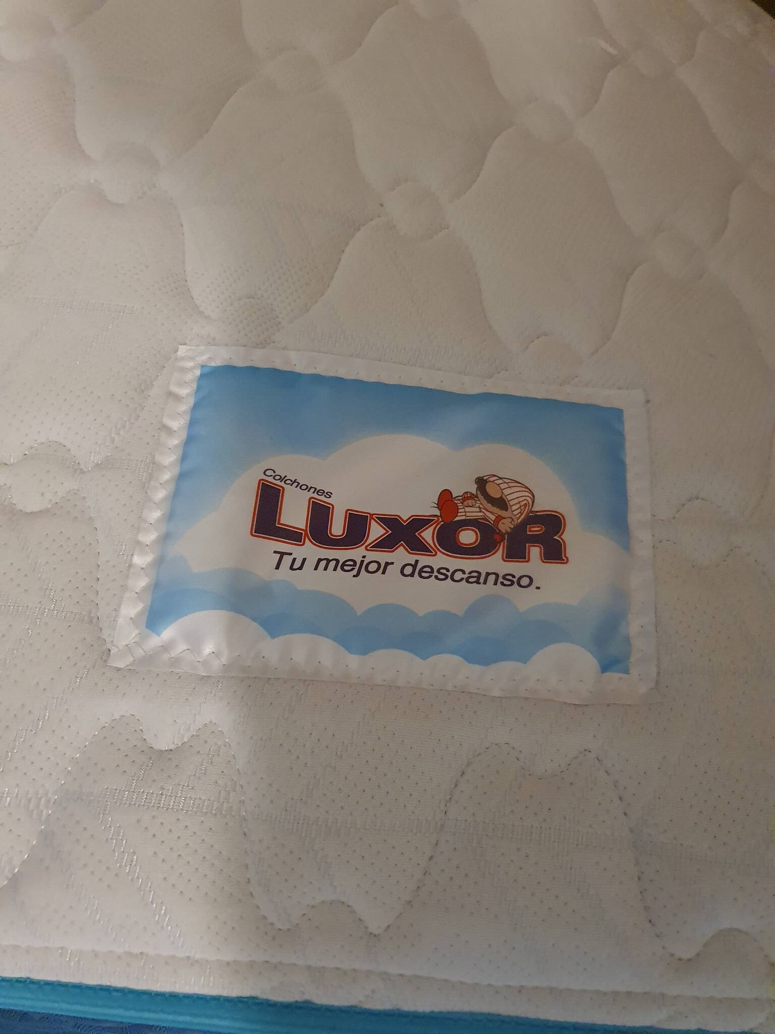 Een LuxoR matras op een bed met een geribbelde witte laken.