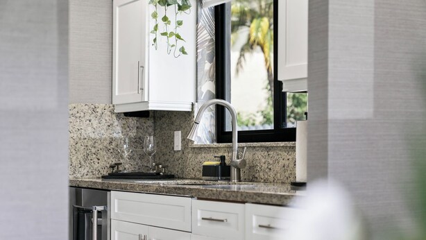 Uma cozinha moderna com bancadas de granito, eletrodomésticos de aço inoxidável e armários brancos.