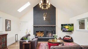 Ein Wohnzimmer mit Kamin, einer Couch, einem Couchtisch und einem an der Wand befestigten Fernseher.