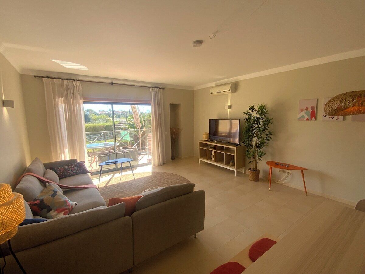 A modern living room with a sofa, TV, and a potted plant.