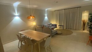 Un salon moderne comprenant une table à manger, un canapé et une grande fenêtre avec des rideaux.