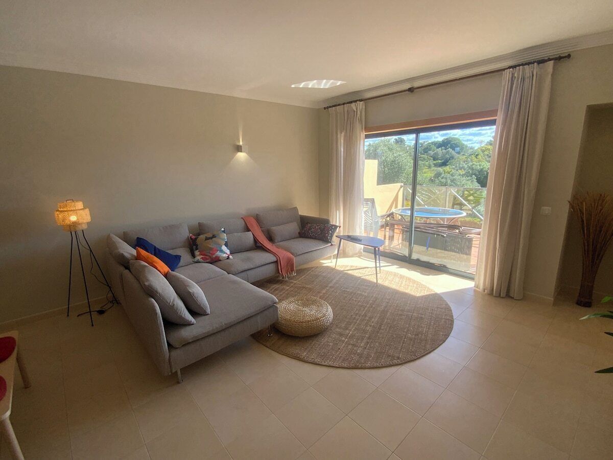 A modern living room with a grey sectional sofa, a round woven rug, and a floor lamp.