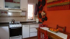 A kitchen with white cabinets, a stove, and a window with blinds. - Sauces Apart (Yerba Buena)