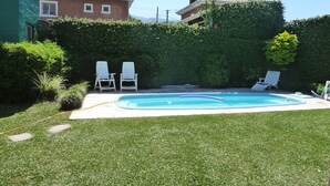 A backyard with a swimming pool, two lounge chairs, and a hedge. - Sauces Apart (Yerba Buena)