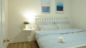 A bedroom with a white bed, a bedside table with a lamp, and two framed pictures on the wall. - Spacious 2-Bed-Room near Yonge & Major Mackenzie (Richmond Hill)