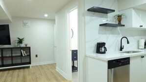 A modern kitchen with white cabinetry, a black countertop, and a built-in dishwasher. - Spacious 2-Bed-Room near Yonge & Major Mackenzie (Richmond Hill)