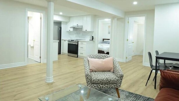 A modern apartment with a kitchen, dining area, and a living room with a leopard print armchair. - Spacious 2-Bed-Room near Yonge & Major Mackenzie (Richmond Hill)