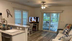 Una cocina moderna con una isla integrada, un área de comedor con televisor y una sala de estar con sofá.